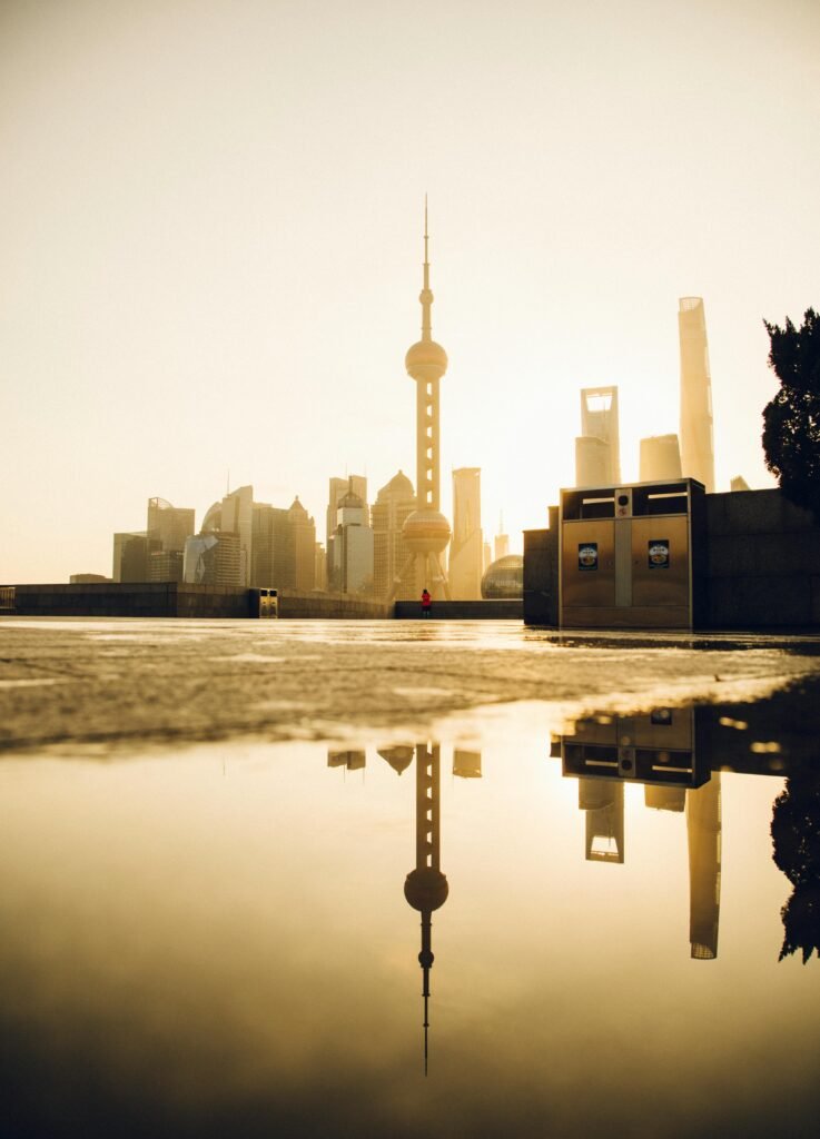 Stunning view of Shanghai's skyline reflecting in a puddle during sunrise, showcasing urban architecture.